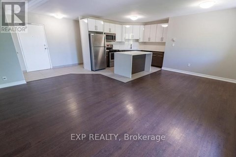 A kitchen with white cabinets and a stainless steel refrigerator.