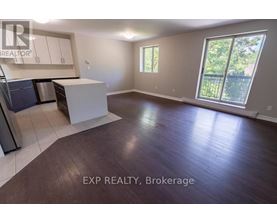 A large empty room with a kitchen area and a window.