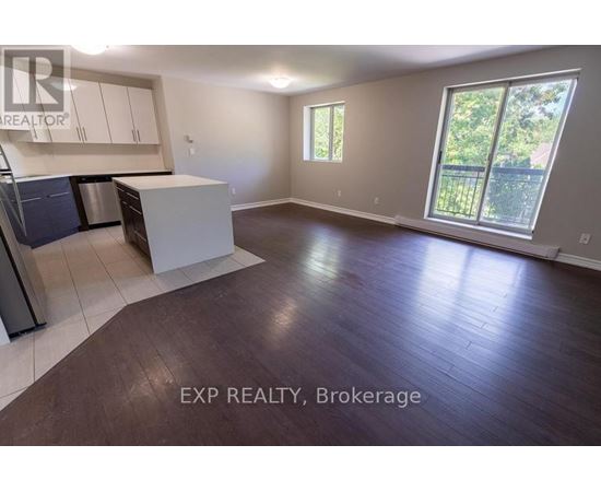 A large empty room with a kitchen area and a window.