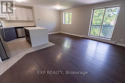 A large empty room with a kitchen area and a window.
