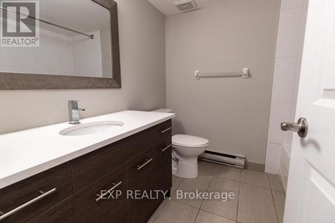 A bathroom with a sink, toilet, and a mirror.