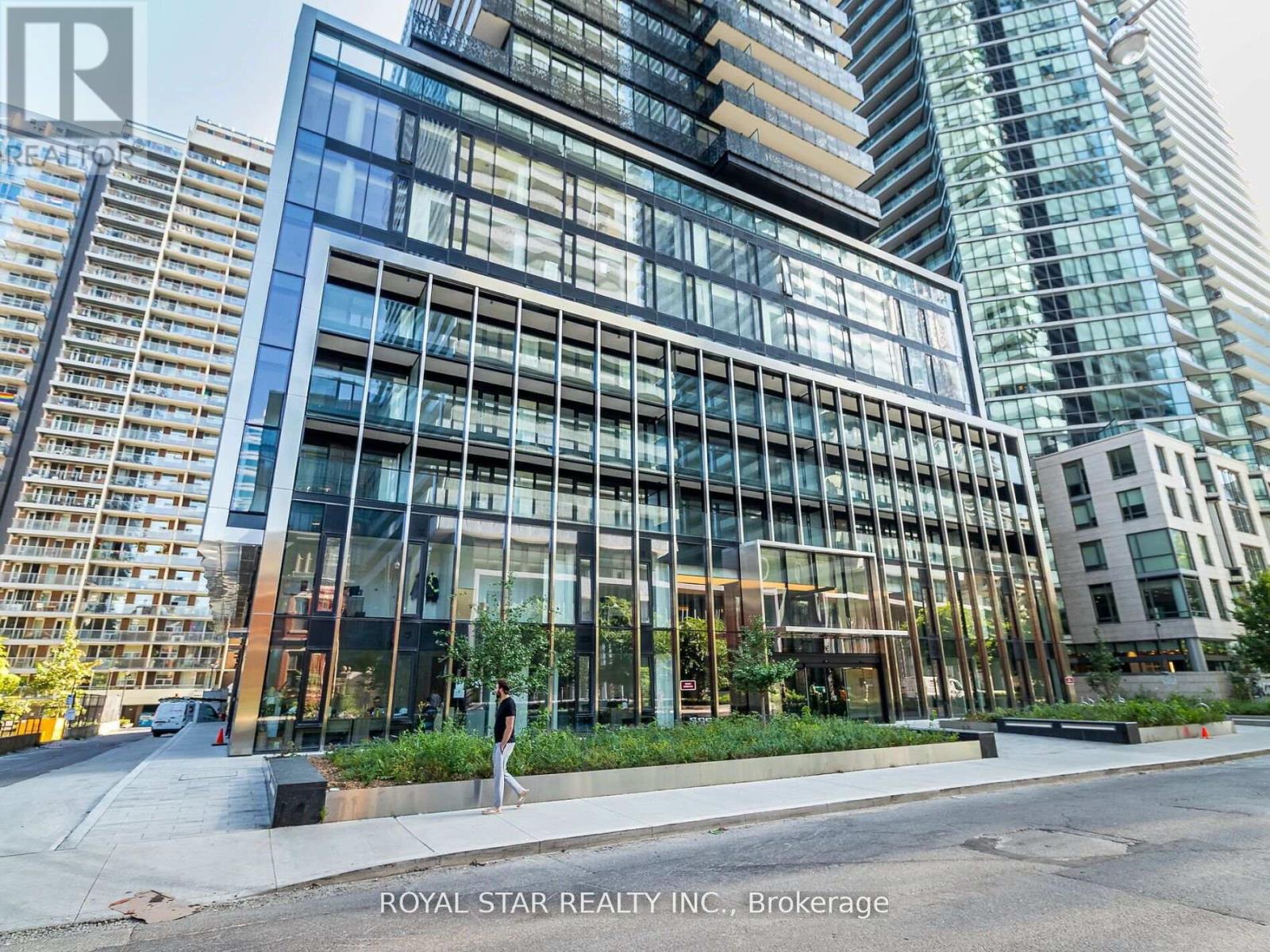 A modern building with glass windows and a person walking in front of it.