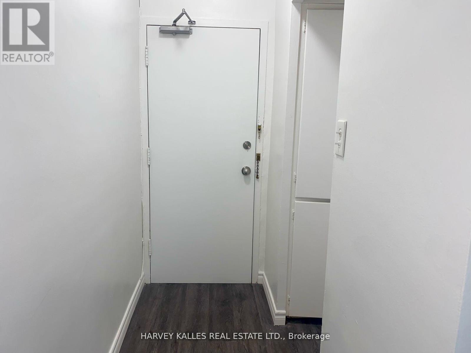 A white door with a black handle is in a white room.