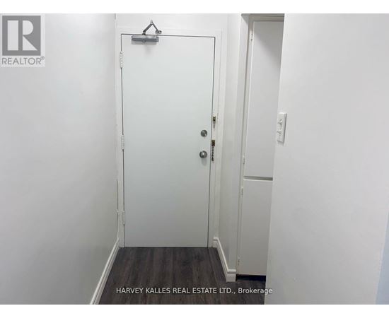 A white door with a black handle is in a white room.