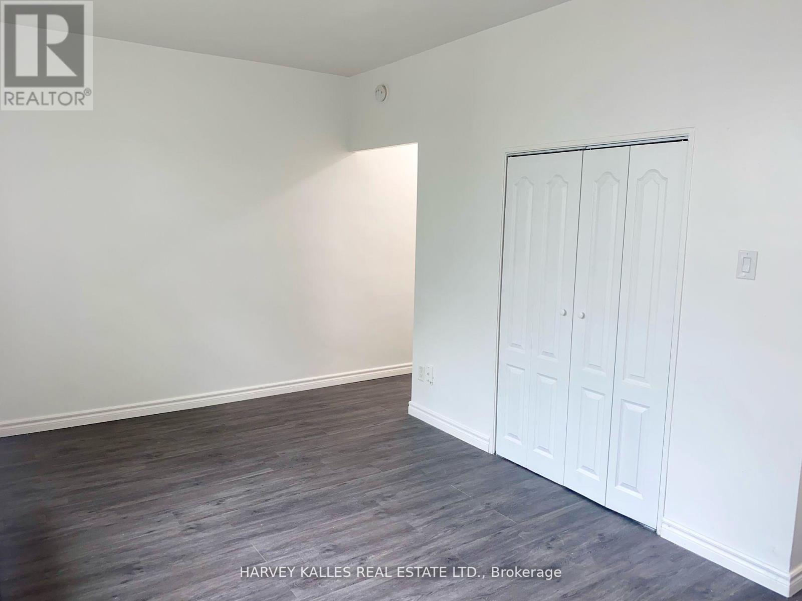 A room with a white door and a grey floor.