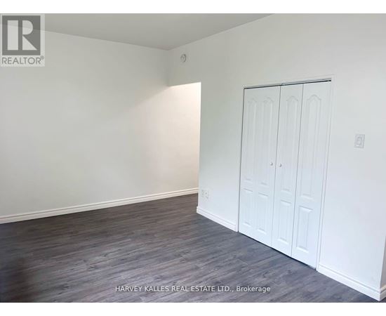 A room with a white door and a grey floor.