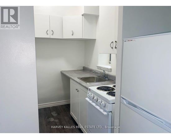 A small kitchen with a stove, sink, and cabinets.