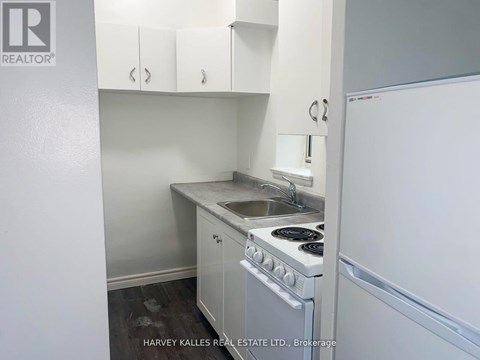 A small kitchen with a stove, sink, and cabinets.