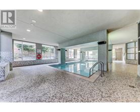 A large indoor swimming pool with a glass barrier and a tiled floor.