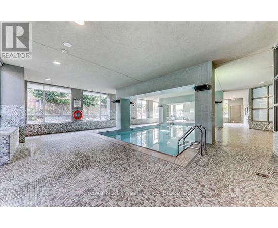 A large indoor swimming pool with a glass barrier and a tiled floor.