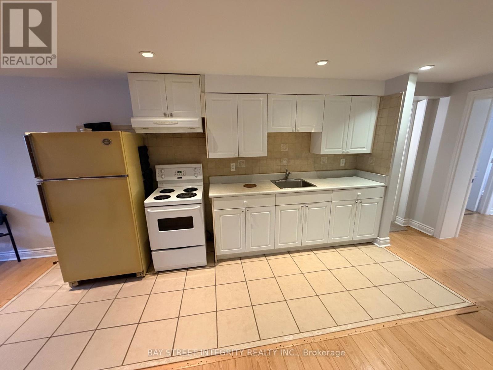 A kitchen with white cabinets and a beige floor.