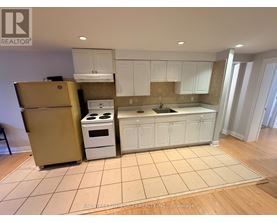 A kitchen with white cabinets and a beige floor.