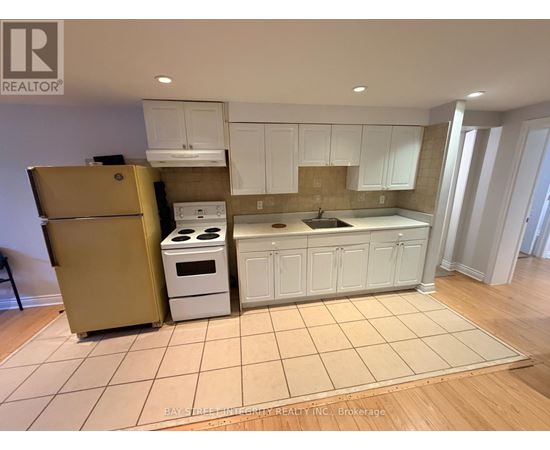 A kitchen with white cabinets and a beige floor.