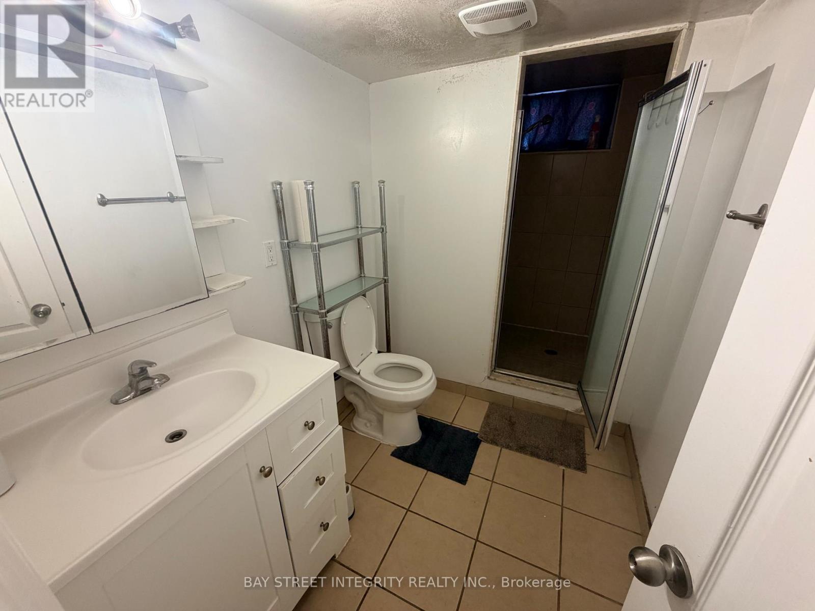 A small white bathroom with a toilet, sink, and shower.