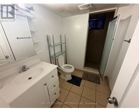 A small white bathroom with a toilet, sink, and shower.
