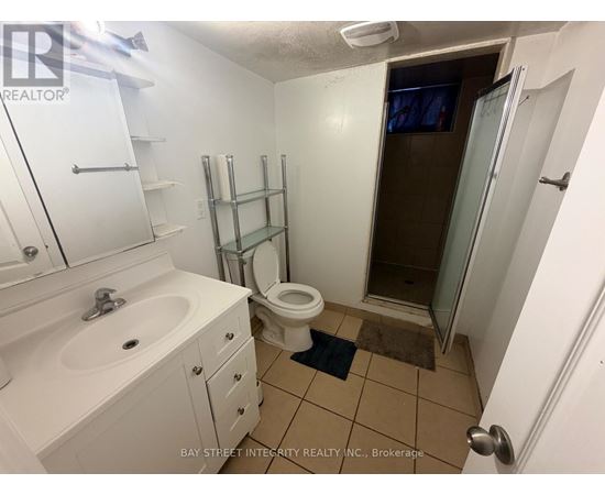 A small white bathroom with a toilet, sink, and shower.