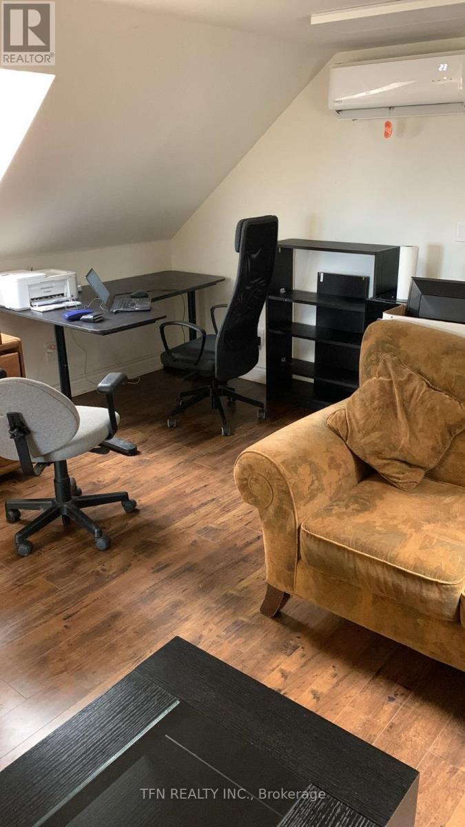 A room with a couch, chairs, and a desk.