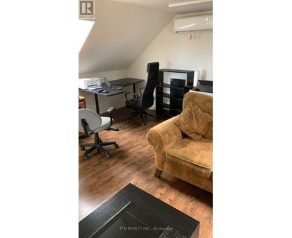 A room with a couch, chairs, and a desk.