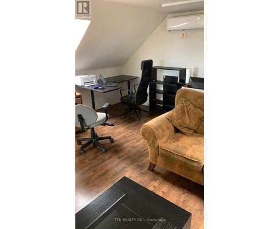 A room with a couch, chairs, and a desk.