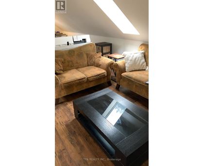 A living room with a tan couch and a glass coffee table.