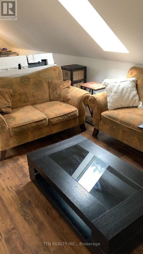 A living room with a tan couch and a glass coffee table.