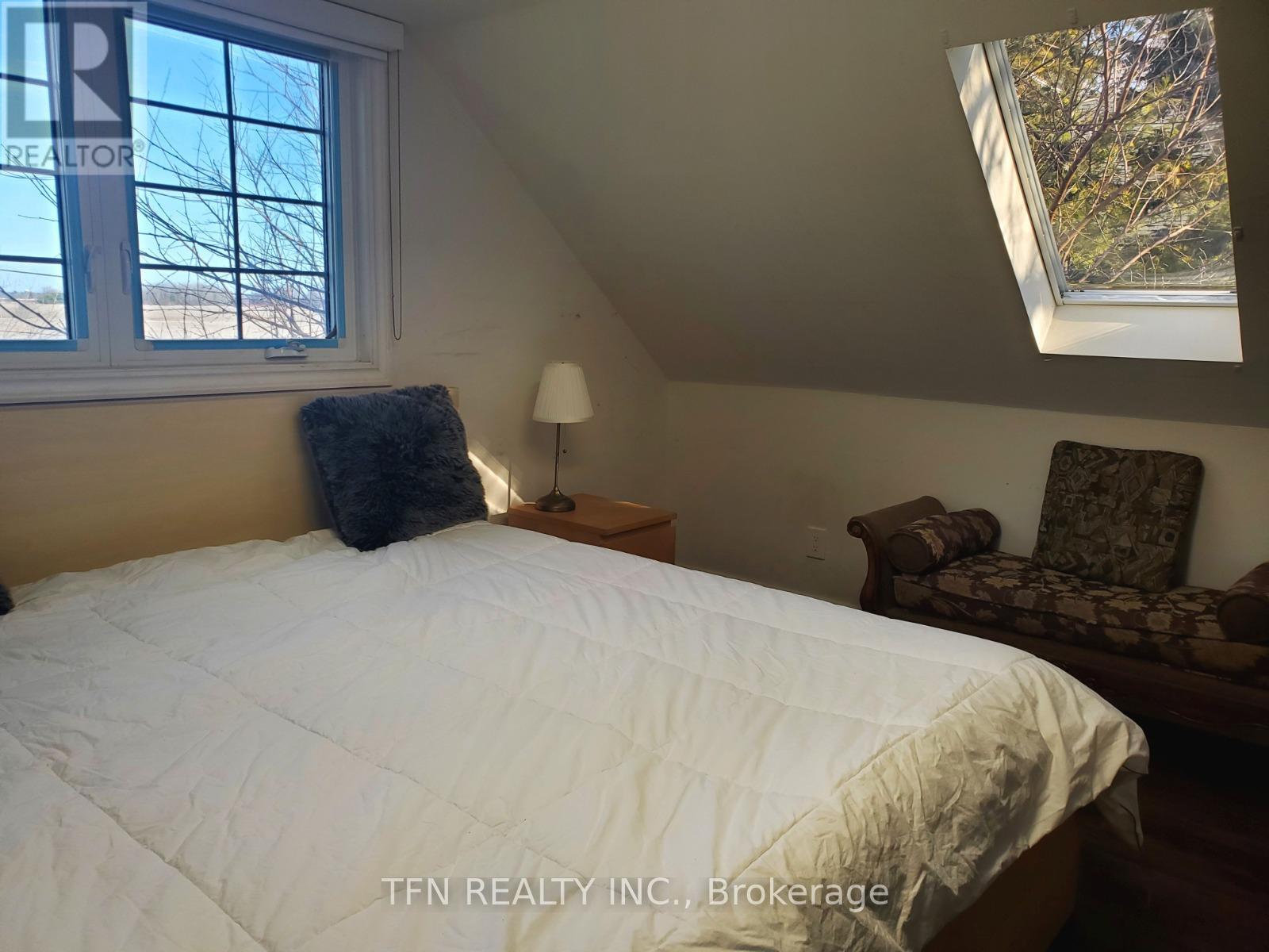 A bedroom with a bed, chair, and window.