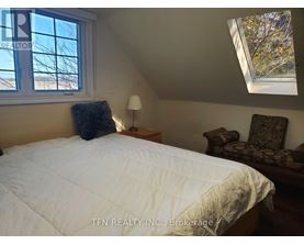 A bedroom with a bed, chair, and window.