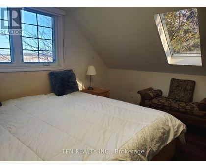 A bedroom with a bed, chair, and window.