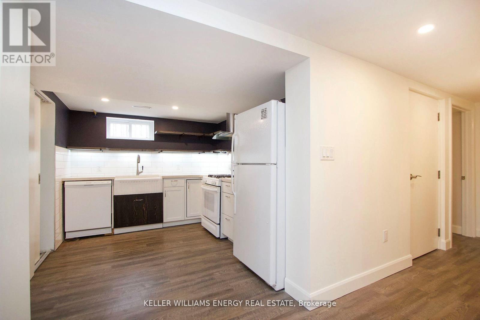 A kitchen with white appliances and wood floors.