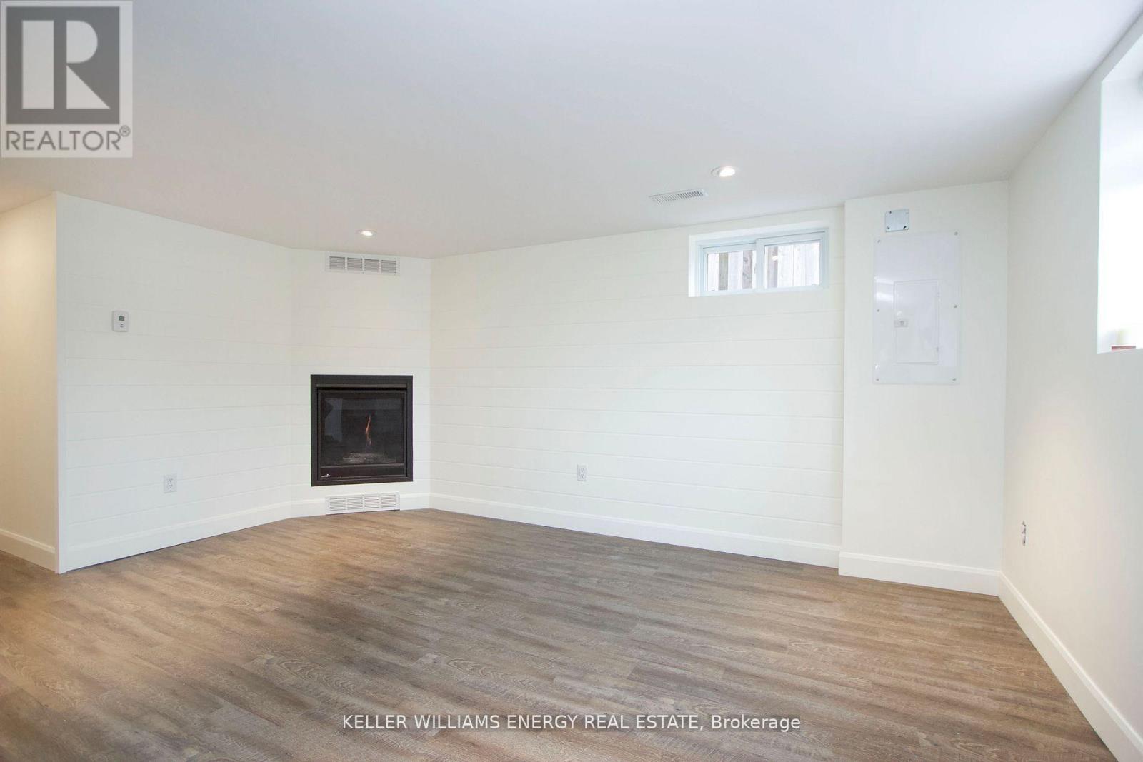 A spacious room with a fireplace and wooden flooring.