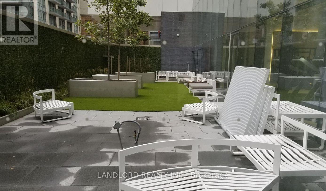 A white outdoor furniture set is displayed in front of a glass building.