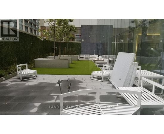 A white outdoor furniture set is displayed in front of a glass building.