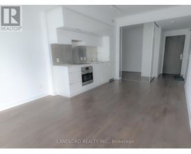 A spacious room with wooden flooring and a built-in stainless steel range hood.