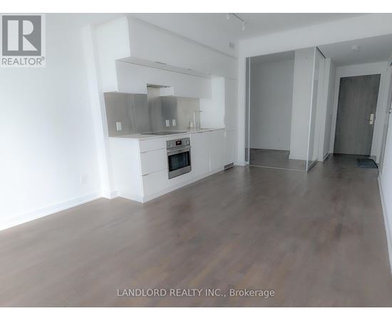 A spacious room with wooden flooring and a built-in stainless steel range hood.