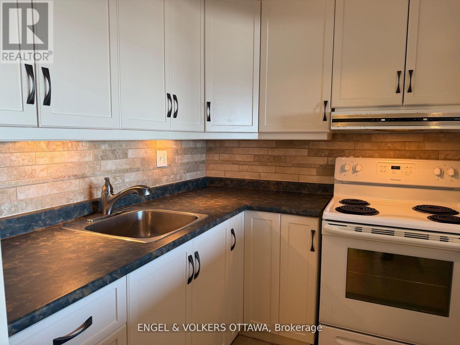 A kitchen with white cabinets and a black countertop.