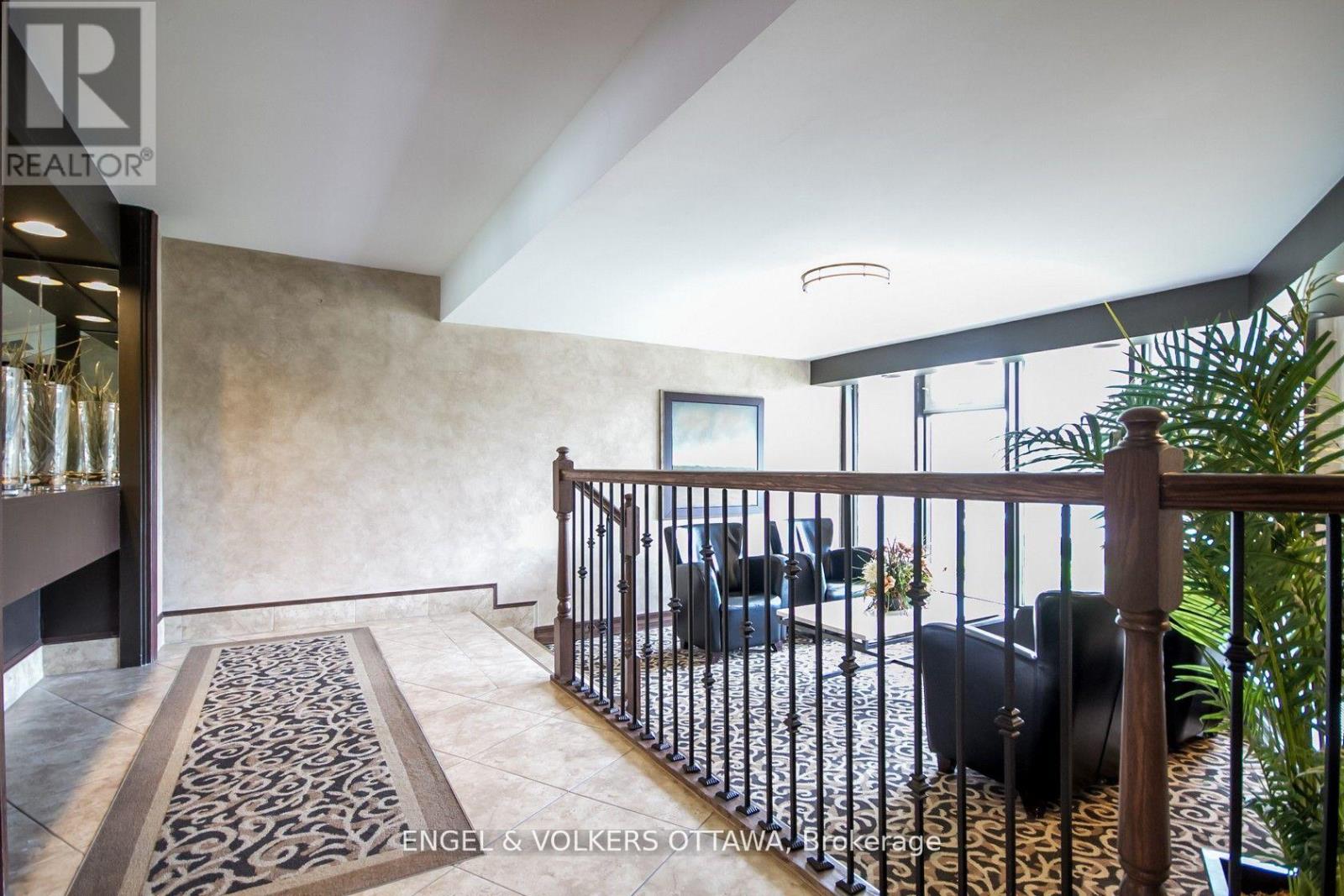 A living room with a black couch and a patterned rug.