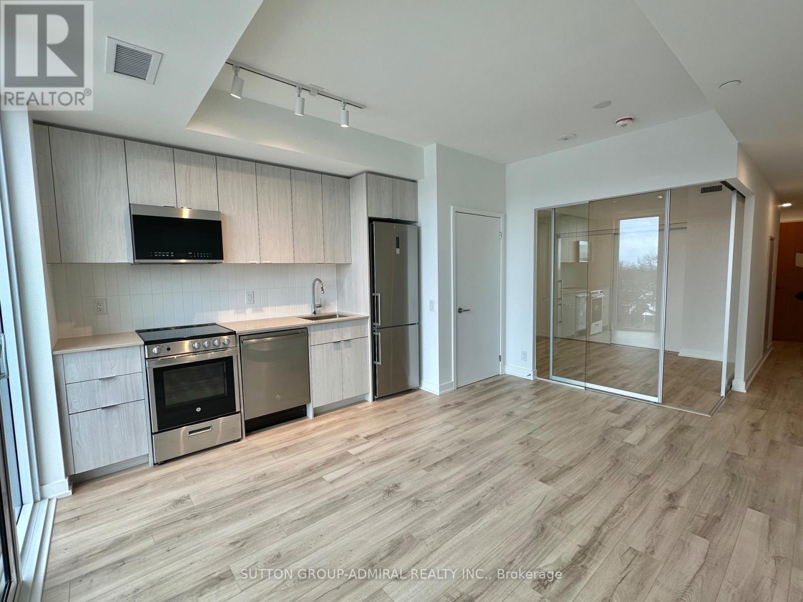 A modern kitchen with wooden floors and stainless steel appliances.