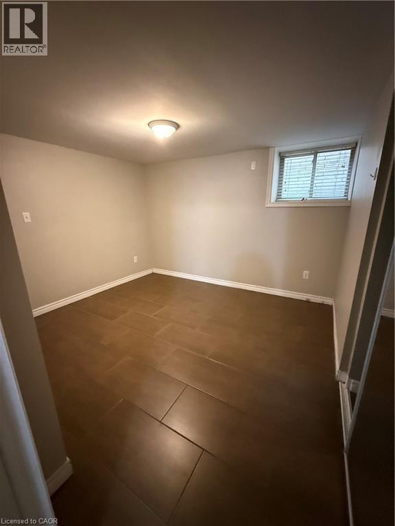 A room with brown tile flooring and a window with blinds.