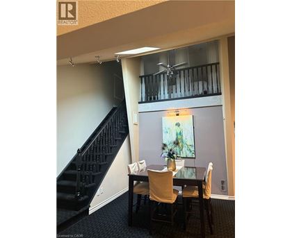 A dining room with a table and chairs and a staircase.