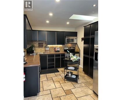 A modern kitchen with black cabinets and a tiled floor.