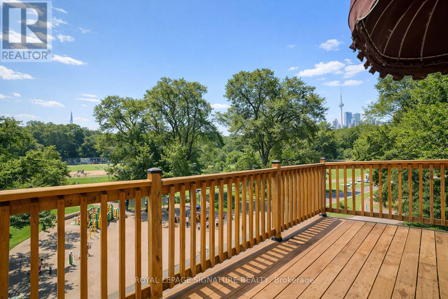 A wooden deck with a view of a park and a city skyline.