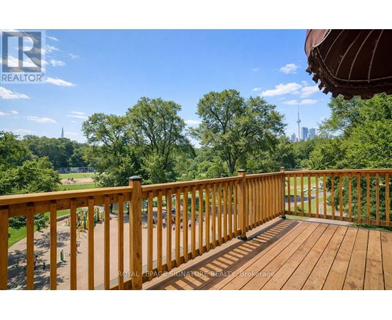 A wooden deck with a view of a park and a city skyline.