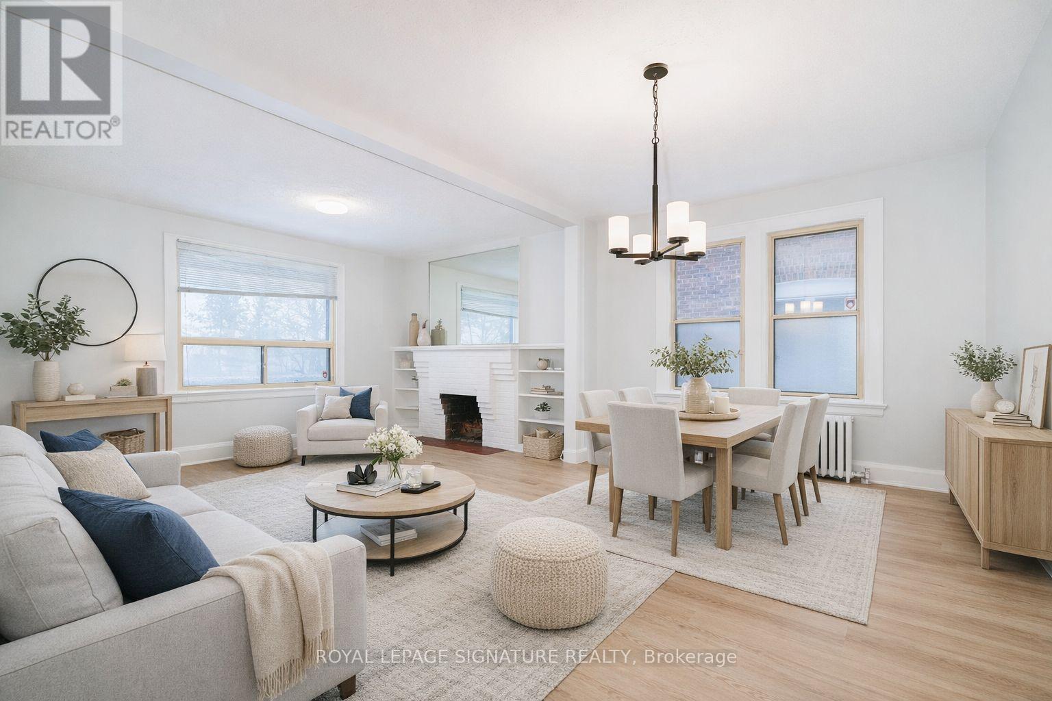 A well-lit, spacious living room with a grey sofa, a coffee table, and a dining table set up.