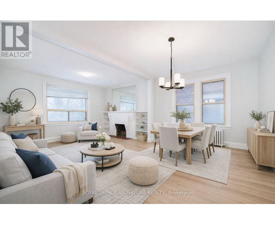 A well-lit, spacious living room with a grey sofa, a coffee table, and a dining table set up.