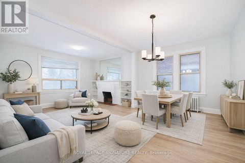 A well-lit, spacious living room with a grey sofa, a coffee table, and a dining table set up.