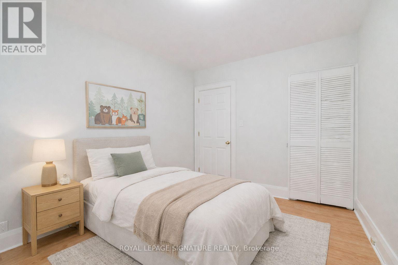 A bedroom with a bed, nightstand, and a painting on the wall.
