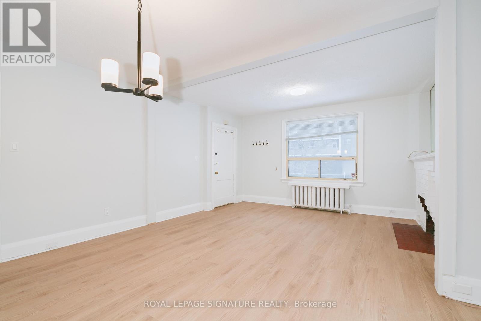 A well-lit, empty room with a window and radiator.
