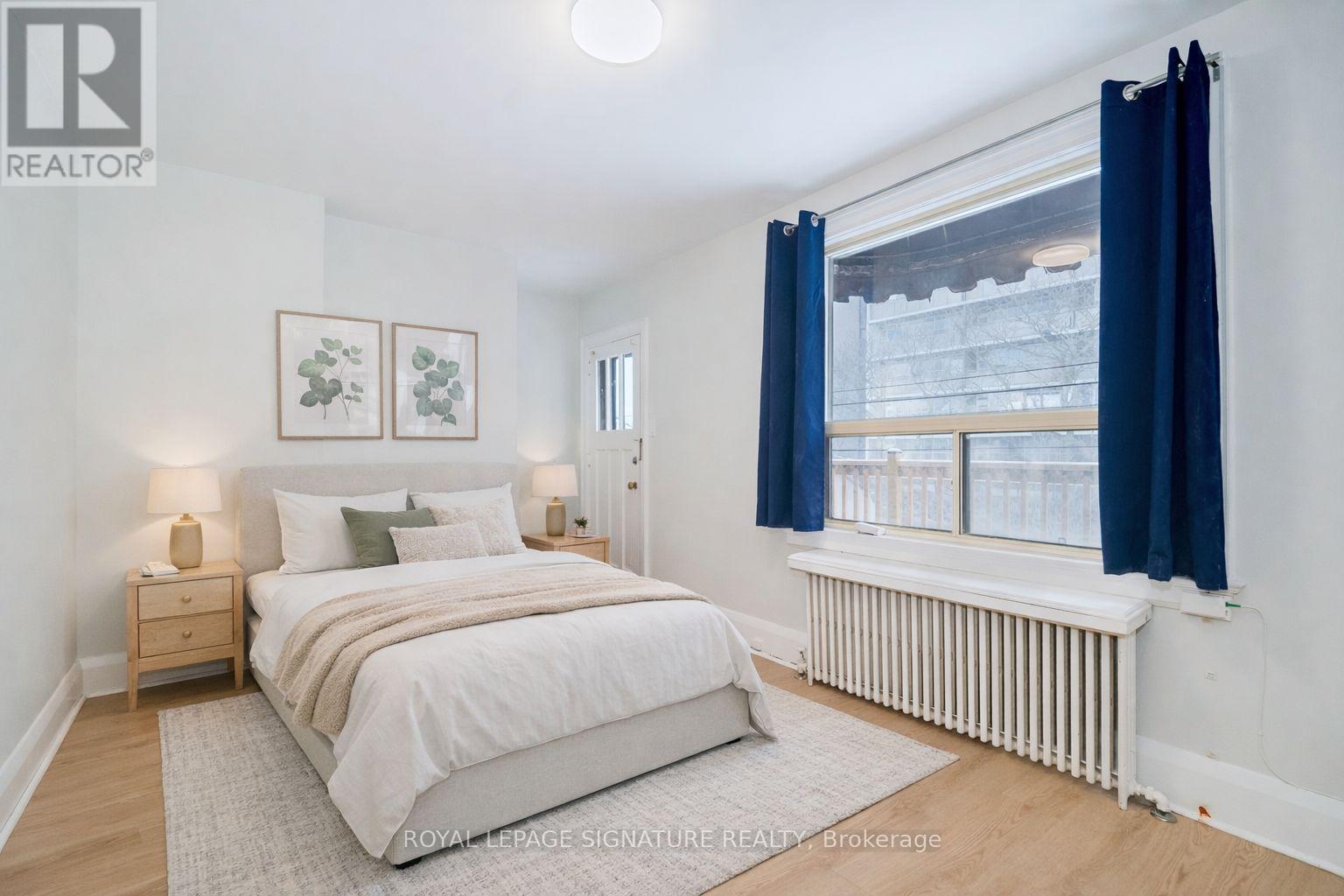 A bedroom with a large bed and a window with blue curtains.