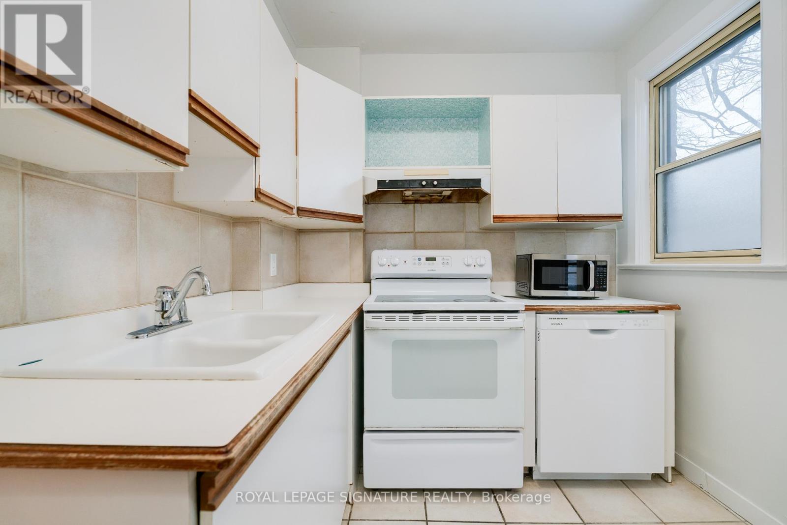 A white kitchen with a sink, oven, and microwave.