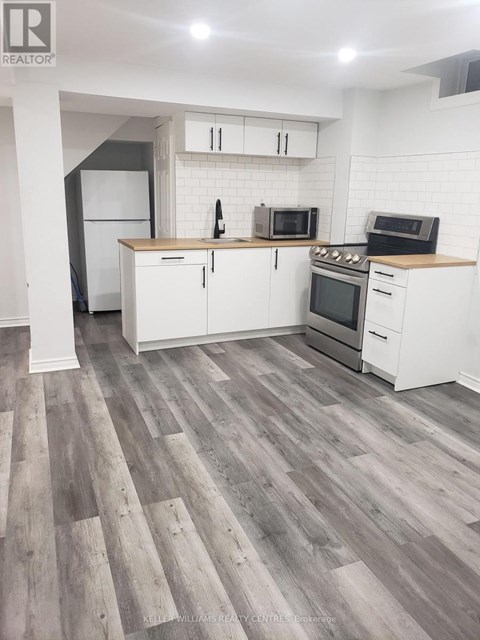A kitchen with white cabinets and a wooden floor.